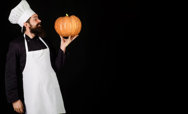 Zdjęcie brodaty szef kuchni w białym fartuchu i kapeluszu z dyniowym jesiennym jedzeniem zdrowe organiczne zbiory warzyw