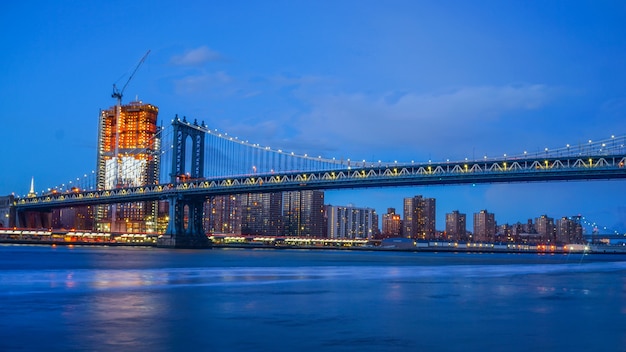 Zdjęcie brooklyn bridge i nyc skylinet noc z odbiciem panoramy east river