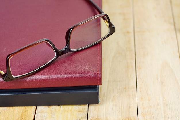 Brown Eyeglasses na stercie książka na drewnianym pracującym stole.