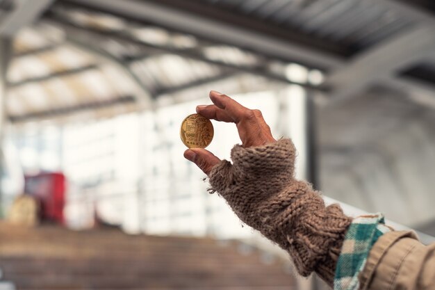 Brudny bezdomny trzymający złotą monetę kryptowaluty