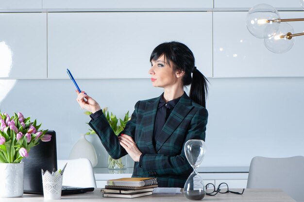 Brunetka bizneswoman w garniturze robi wykład lub spotkanie pokazuje coś długopisem