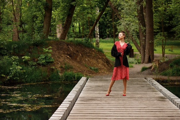 Brunetka dama w parku w letni wieczór idzie na randkę. stylowe ubrania na imprezę