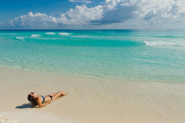 Brunetka dziewczyna w jasnym stroju kąpielowym na plaży w Cancun w Meksyku