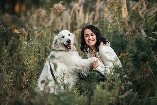 Brunetka dziewczyna z białym psem golden retriever w polu