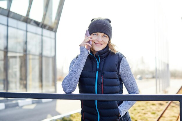 Brunetka fitness kobieta w odzieży sportowej rozmawia przez telefon komórkowy na zewnątrz sport zdrowy styl życia