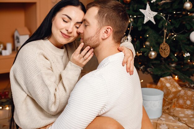 Brunetka i brodaty mężczyzna siedzący w pobliżu choinki i przytulający się