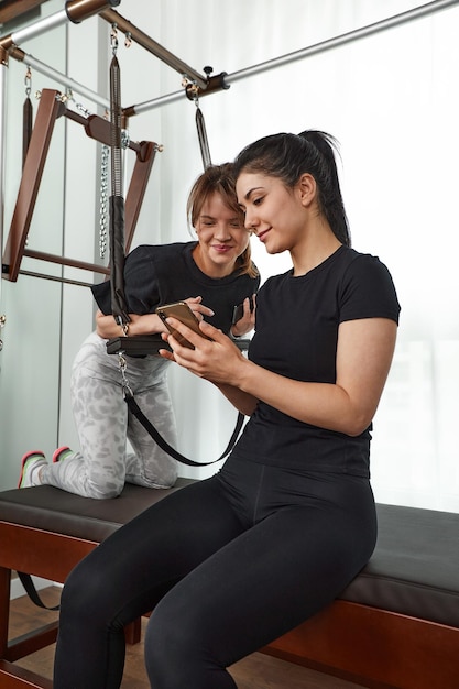 Brunetka kaukaska kobieta osobisty trener podczas sesji treningowej na sprzęt do pilates reformer łóżko z atrakcyjnym klientem w gabinecie lekarskim światła Koncepcja rehabilitacji zdrowego stylu życia