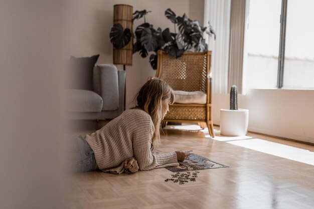 Brunetka kobieta grająca w puzzle na podłodze, zdjęcie hobby