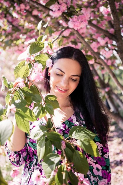 Brunetka kobieta w ogrodzie w pobliżu sakura na wiosnę