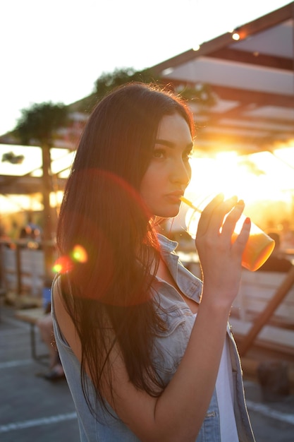 Brunetka pije świeży sok przez słomkę