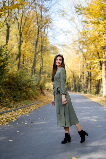 Brunetka portret kobiety w parku jesienią na sobie oliwkową sukienkę