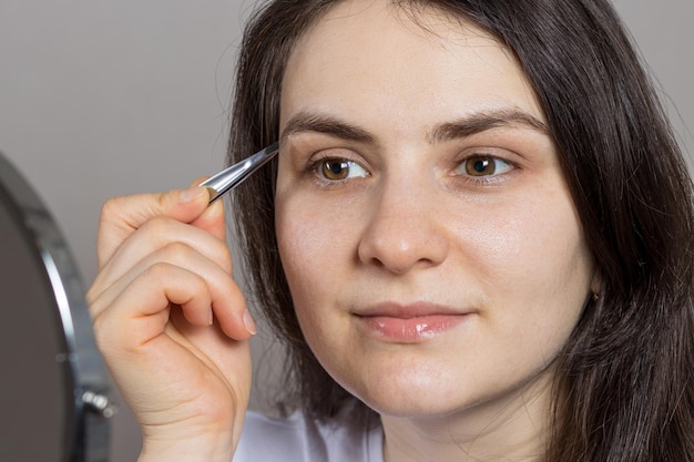 Brunetka wyskubała brwi przed lustrem