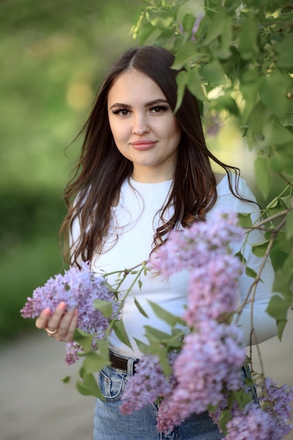 Brunetka z długimi włosami w krzakach bzu na wiosnę