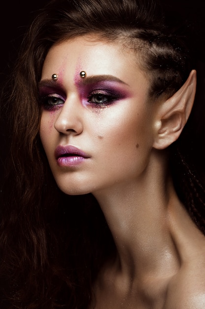 Zdjęcie brunetka z kreatywnymi warkoczami, makijażem artystycznym i uszami elfa. piękna twarz.
