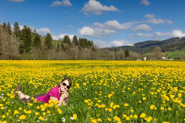 Zdjęcie brunetki kobieta kłama na polu żółty dandelion.