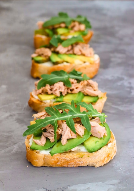 Bruschetta Ciabatta z twarogiem, awokado, tuńczykiem i rukolą na betonie