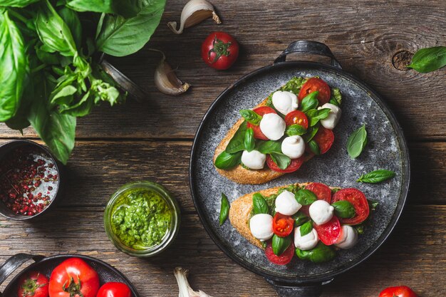 Bruschetta z mozzarellą, pomidorami, bazylią i pesto na talerzu Bruschetta Caprese