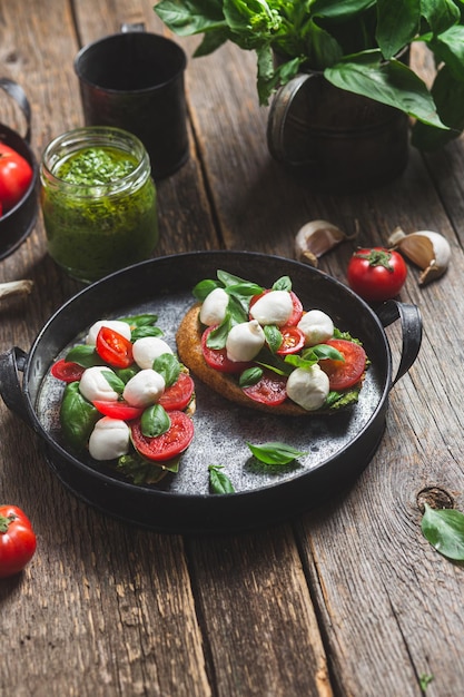 Bruschetta z mozzarellą, pomidorami, bazylią i pesto na talerzu Bruschetta Caprese