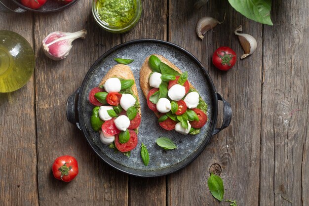 Bruschetta z mozzarellą, pomidorami, bazylią i pesto na talerzu Bruschetta Caprese