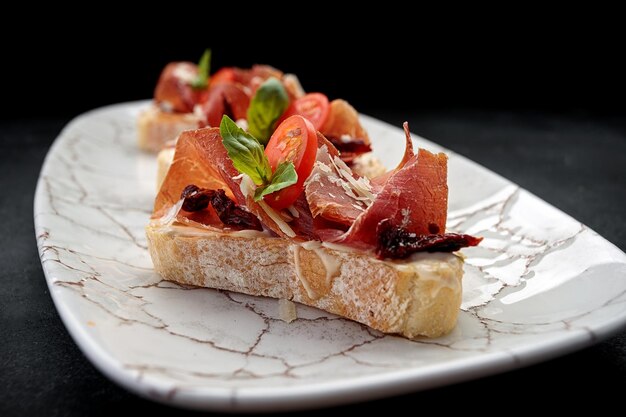 Bruschetta z parmą i sosem na talerzu na ciemnym tle