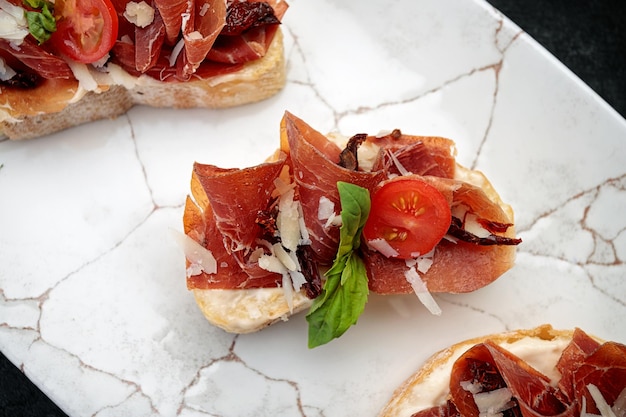 Bruschetta z parmą i sosem na talerzu na ciemnym tle