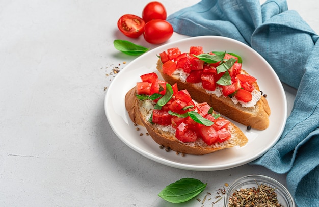 Bruschetta z pomidorami, fetą i bazylią na szarym tle. Włoska przystawka, antipasti.