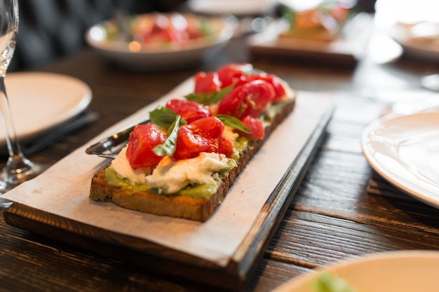 Bruschetta z pomidorami na drewnianym stojaku.