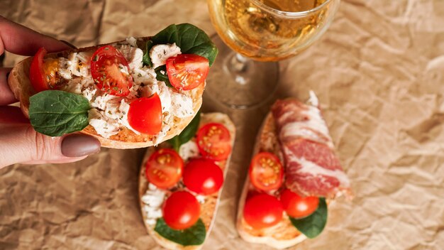 Zdjęcie bruschetta z pomidorkami koktajlowymi. kieliszek do wina, włoska przystawka. tło papieru rzemiosła. koncepcja piknikowa