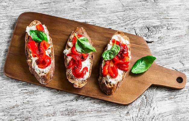 Zdjęcie bruschetta z serem feta pieczoną czerwoną słodką papryką i bazylią na jasnym drewnianym tle