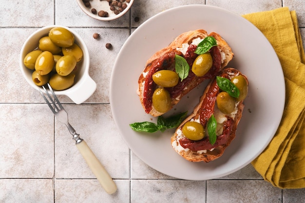 Bruschetta Z Suszonymi Pomidorami Tosty Lub Kanapka Z Ricottą Z Suszonymi Pomidorami I Ziołami Prowansalskimi Z Bazylią Podane Na Talerzu Na Szarym, Starym, Popękanym Stole, Widok Z Góry Przepis Na Baner Menu