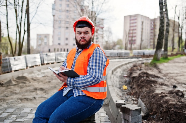 Brutalny Broda Pracownika Mężczyzna Kostiumu Pracownik Budowlany W Pomarańczowym Hełmie Bezpieczeństwa Siedzi Na Chodniku I Sprawia, że Wpisy Pracy Notebooka