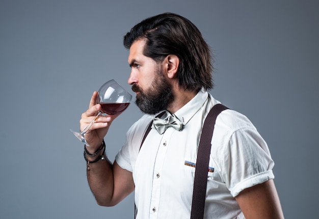 Brutalny brodaty mężczyzna o stylowym wyglądzie pije wino