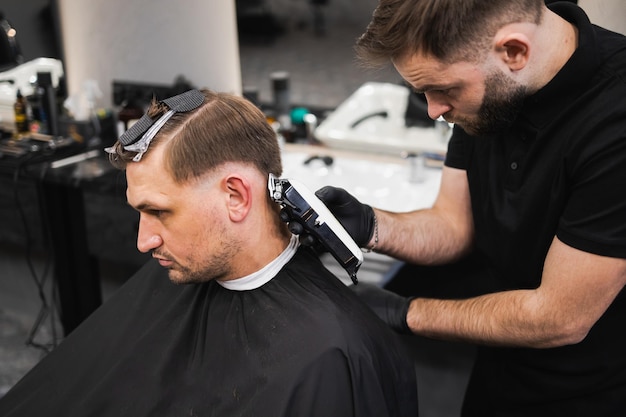 Brutalny fryzjer przycinający klientom włosy maszynką do strzyżenia