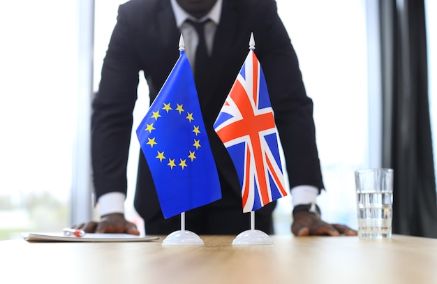 Brytyjska flaga i flaga Unii Europejskiej z biznesmenem w pobliżu. Brexit