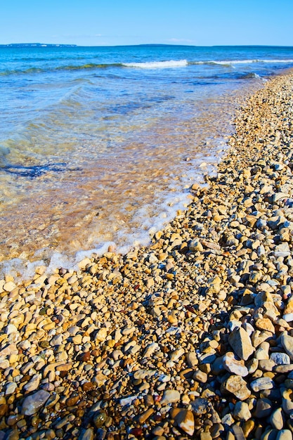 Brzeg jeziora z odległymi falami i kamieniami na plaży