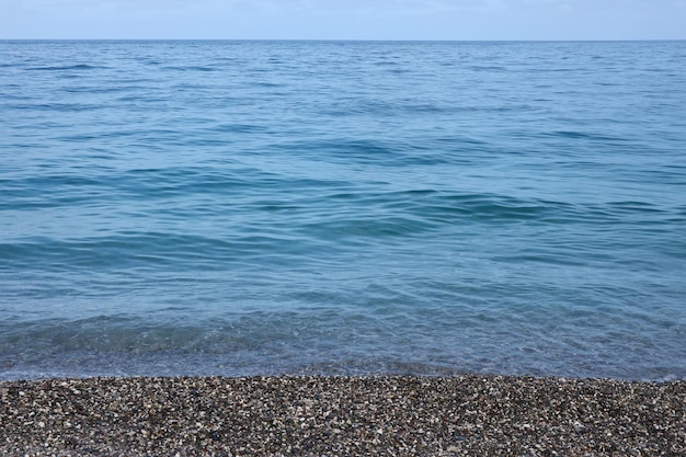 Brzeg kamyków z morzem i plażą w tle