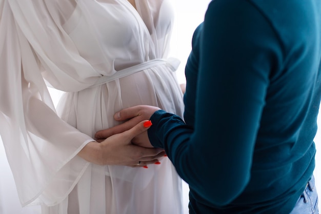 Brzuch kobiety w ciąży jest trzymany przez męskie ręce