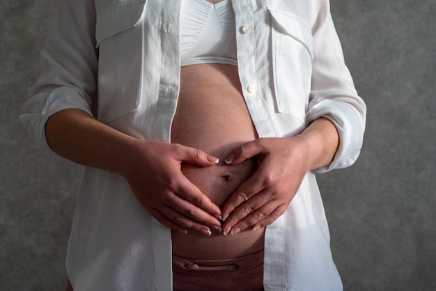 Brzuch kobiety w ciąży koncepcja ciąży kobieta trzymająca się za ręce w kształcie serca