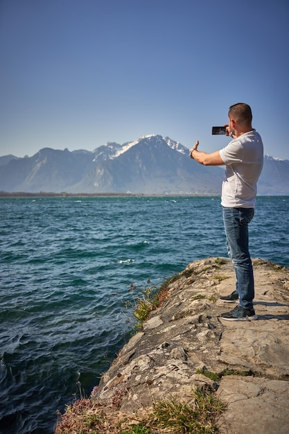Brzydki mężczyzna robi sobie selfie w szwajcarskim jeziorze