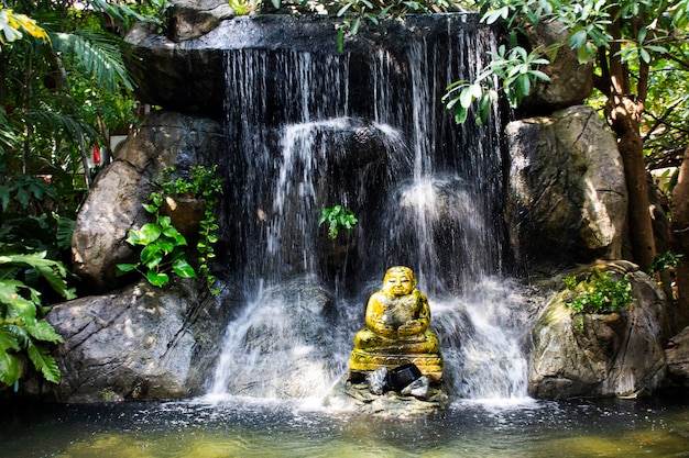 Buddyjski Gautama lub Gautama Maha Katyayana Buddyzm tajska nazwa Phra sangkajai w małych wodospadach dekoruje gadening w parku ogrodowym w świątyni Wat Khae i rezydencji Khun Phaen w Suphan Buti Tajlandia