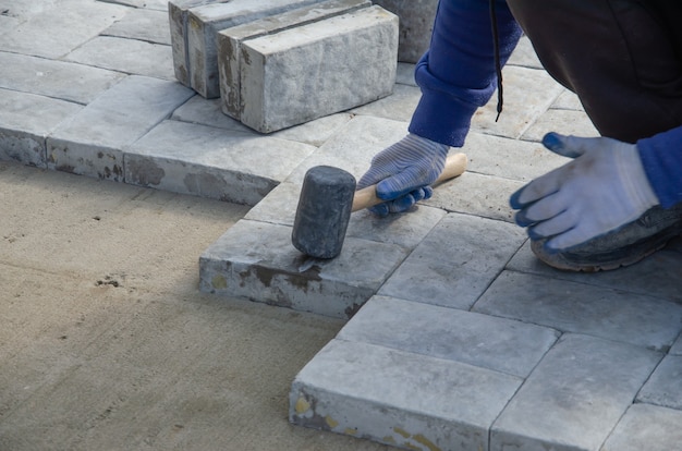 Zdjęcie budowa chodnika przy domu. murarz układa betonową kostkę brukową do budowy chodnika