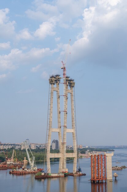 Budowa mostu przez rzekę wraz z podporami, elementami konstrukcyjnymi, dźwigami