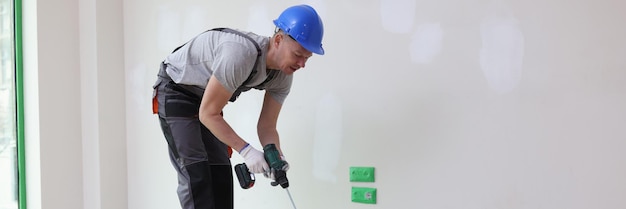 Budowniczy w pokoju miesza farbę w wiadrze remont mieszkania przygotowuje się do malowania ściany w