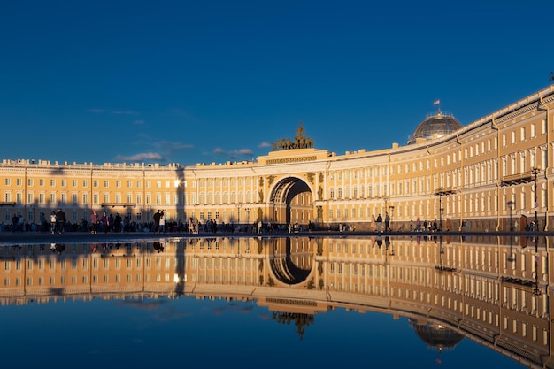 Budynek głównej siedziby odbijający się w kałuży z tłumem chodzących ludzi Sankt Petersburg Rosja