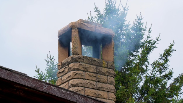 Budynek mieszkalny na przedmieściach w pochmurny dzień w zimną zimę zanieczyszcza powietrze gęstym ciemnym dymem Smog wychodzący z komina