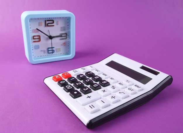 Budzik i kalkulator na fioletowym tle