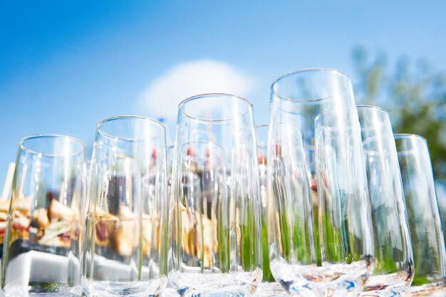 Bufet na świeżym powietrzu - puste szklanki na tle zimnych przekąsek na tle nieba czekają na gości