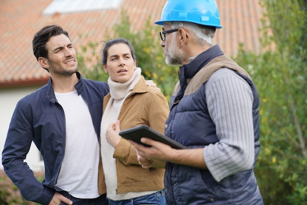 Builder Przegląda Plany Na Zewnątrz Z Właścicielami Domów