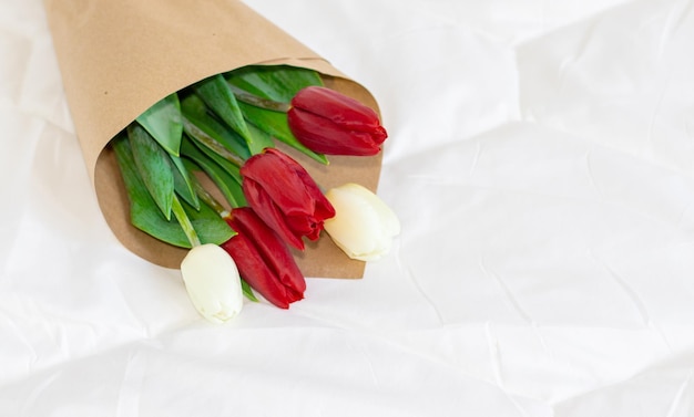 bukiet biało-czerwonych tulipanów na białym kocu na łóżku świętuj walentynki
