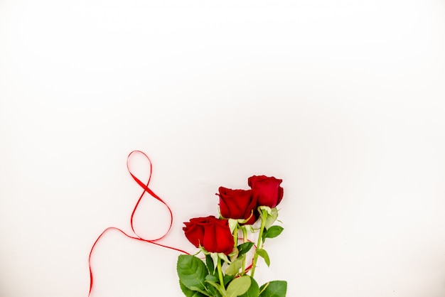 Bukiet czerwonych róż z czerwoną wstążką.